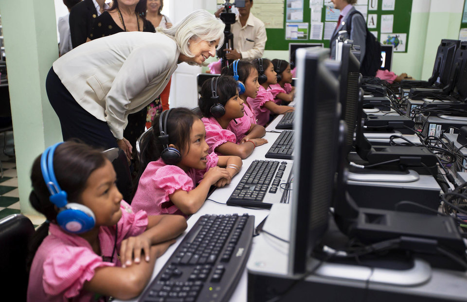 KANDAL PROVINCE, CAMBODIA - DECEMBER 3: In this handout photo provided by IMF, International Monetary Fund Managing Director Christine Lagarde watches school girls in the computer room at Toutes a l'Ecole school on December 3, 2013 in Kandal province, Cambodia. Lagarde is on a three country visit to Asia. (Photo by Stephen Jaffe/IMF Photograph via Getty Images)