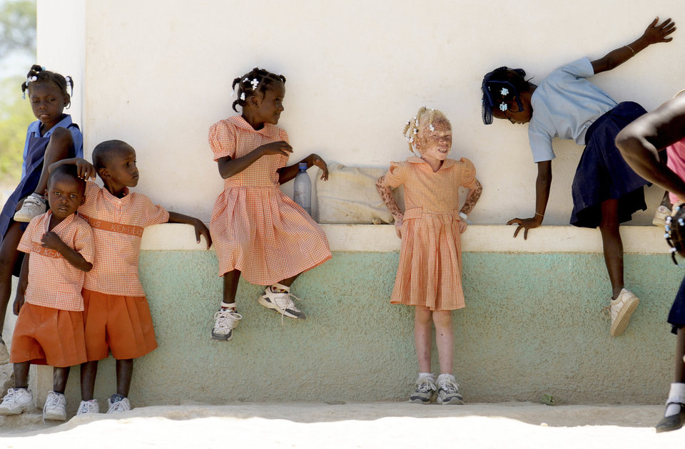 HAITI, Isla de la Laganave, School childrem in uniform playing, including an Albino girl.