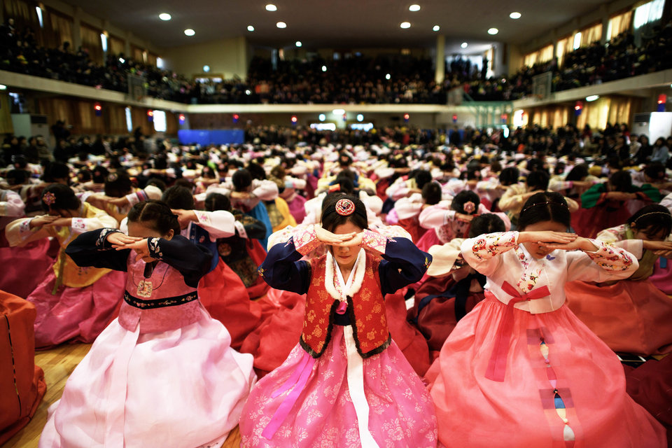 Students wearing traditional hanbok dresses bow as they attend a graduation and coming-of-age ceremony at the Dongmyeong girl's high school in Seoul on February 12, 2015. Around 500 students attended the ceremony, which signifies a child's passage into adulthood and aims to teach participants etiquette and the acceptance of responsibilities. Once a widespread tradition, coming-of-age ceremonies are increasingly rare with the event now usually observed in various less traditional ways. AFP PHOTO / Ed Jones (Photo credit should read ED JONES/AFP/Getty Images)